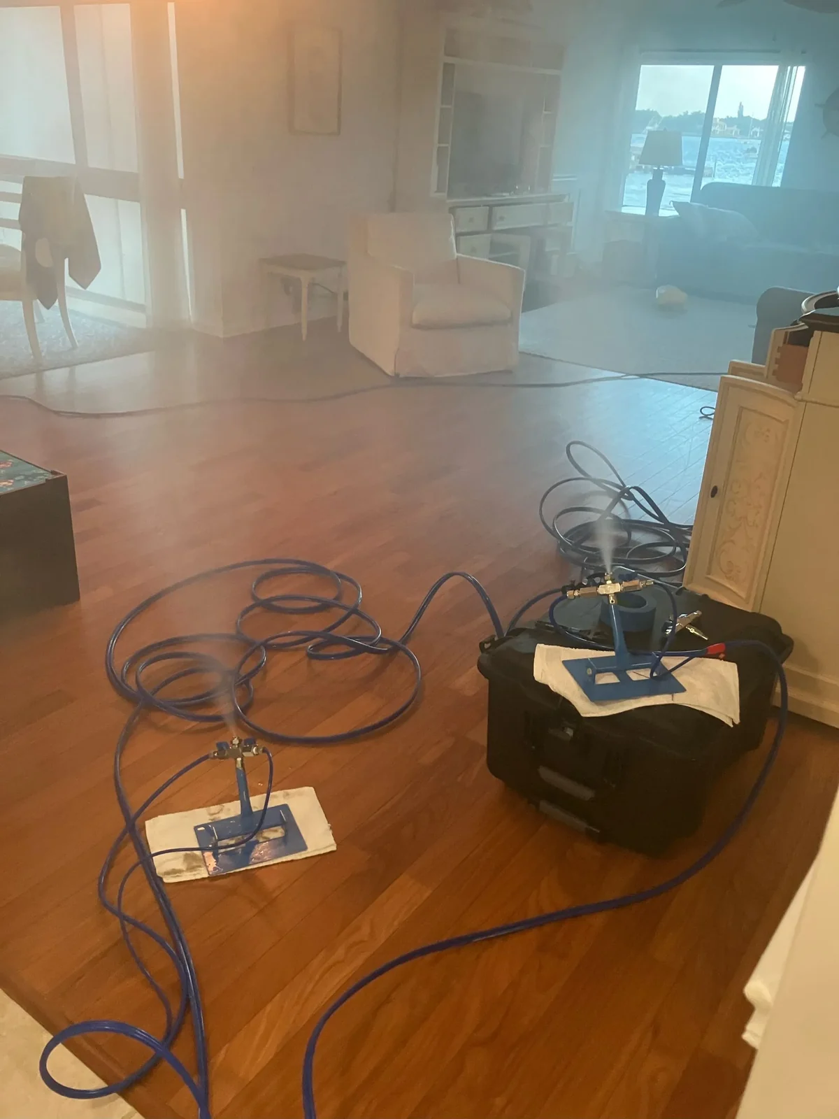 Living room with treatment equipment and hoses running across the floor during a Palm Beach County job